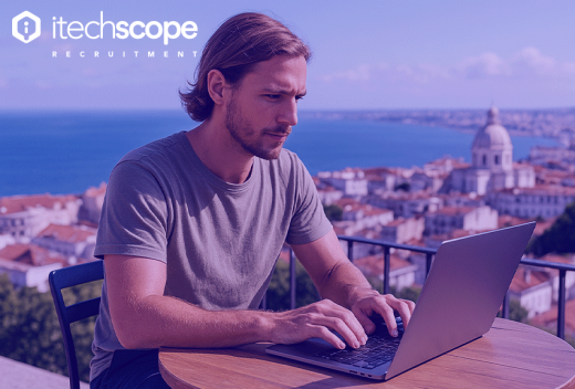 Man on computer doing work out side with a backdrop of a city landscape behind him.